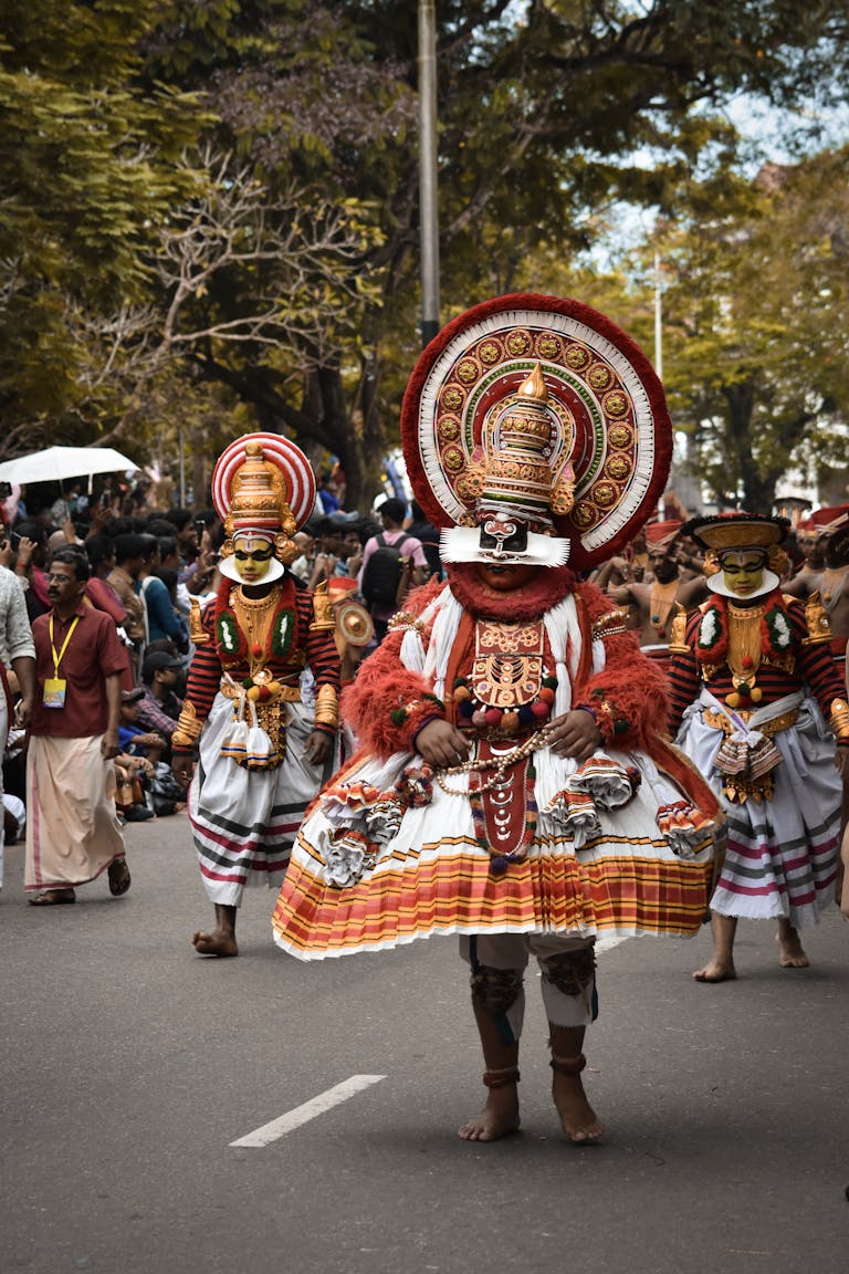 Traditional dancers in ornate costumes celebrate a cultural festival in Kerala, India.