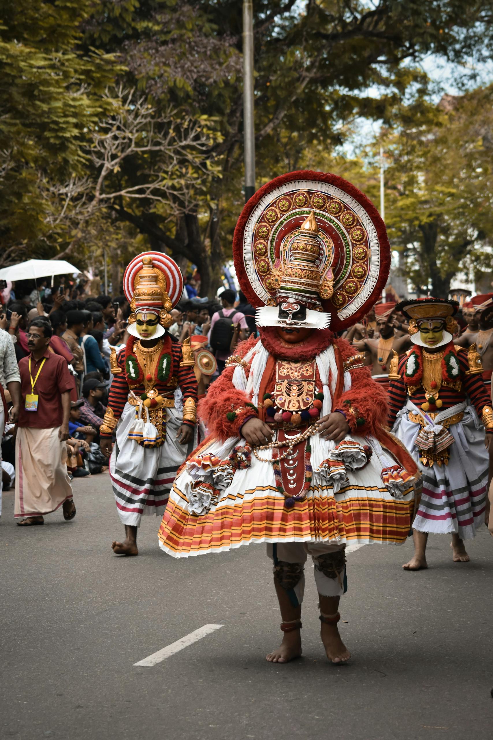 Traditional dancers in ornate costumes celebrate a cultural festival in Kerala, India.