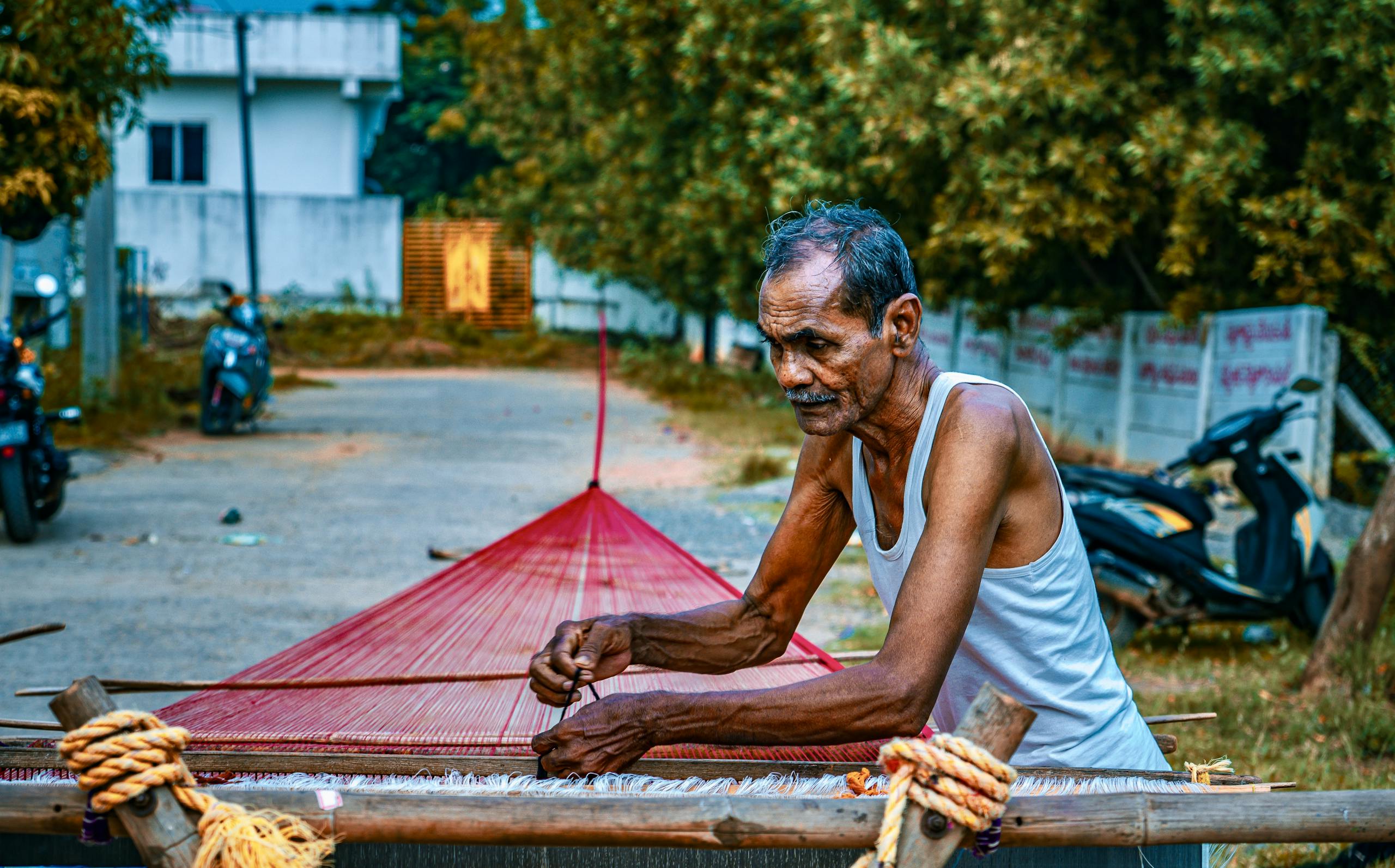 An elderly man skillfully weaving traditional fabric on the street in Mangalagiri, India.