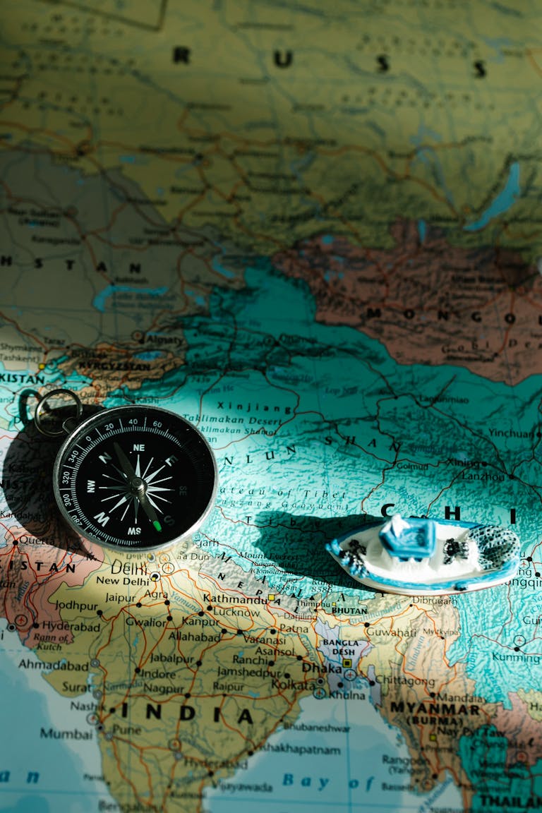 An overhead view of a map with a compass and toy boat symbolizing navigation and travel.