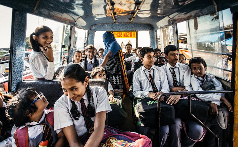 Group of school children in uniforms on a bus in Wadgaon, India.