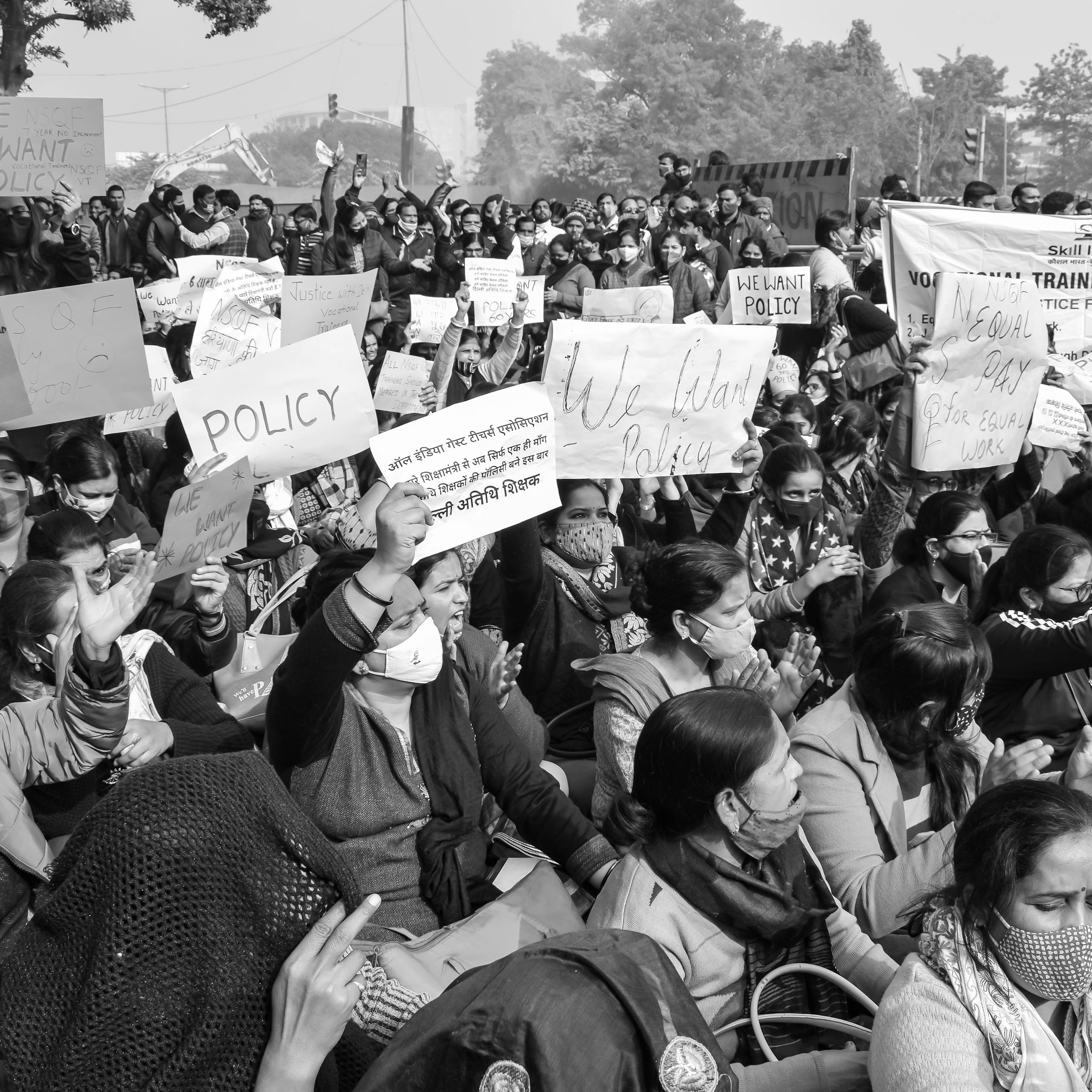 A powerful black and white image of a large protest rally demanding policy change in India.